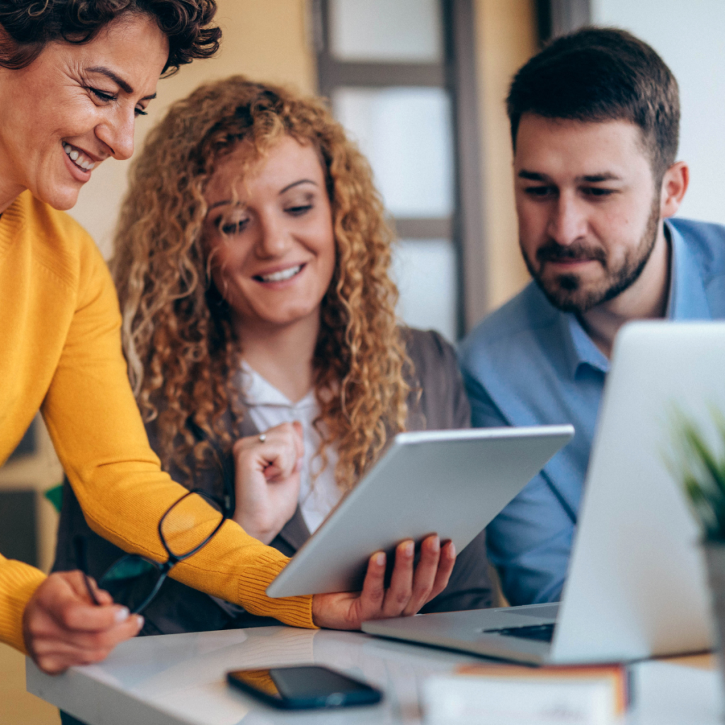 Three business professionals reviewing a tablet together.