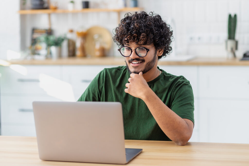 Someone working on a laptop, smiling at what they are looking at.