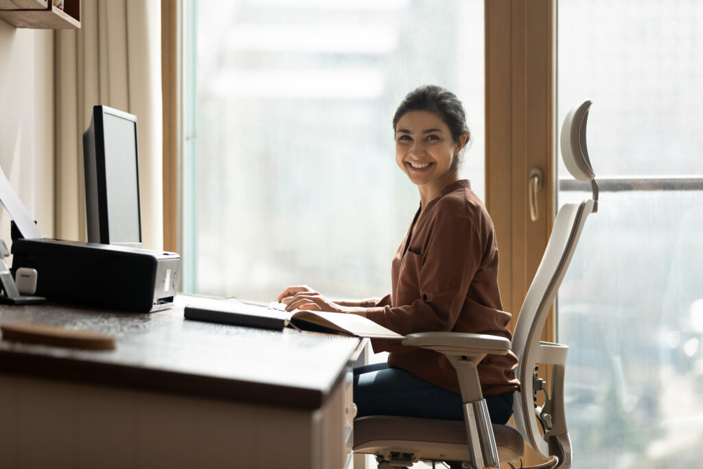 Someone sitting at a desk, smiling at the camera
